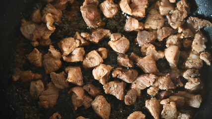 Pieces of meat are fried in a pan. Home kitchen. Close-up.