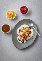 Indian tasty street food Dahi Bhalla or  Dahi Vada garnished with tamarind sauce and pomegranate seeds 