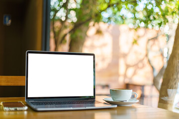 Mockup of laptop computer with empty screen with coffee cup and smartphone on table of the coffee shop background,White screen