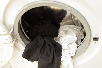 Dark and white clothing mix in front loaded washing machine can with stainless steel rotor and...
