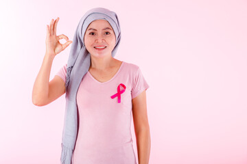 Fototapeta na wymiar a asian women disease mammary cancer patient in pullover holding pink ribbon and hand showing ok sign isolated on pink blank copy space studio background,healthcare,medicine concept