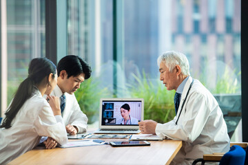 Obraz premium 海外の医師とオンライン会議をする医師たち
