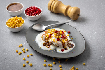 Indian tasty street food Dahi Bhalla or  Dahi Vada garnished with tamarind sauce and pomegranate seeds 