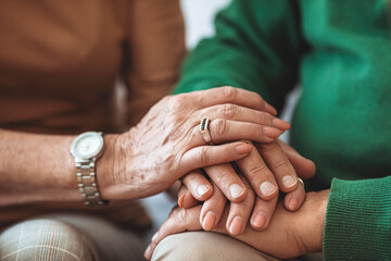 Cropped shot of elderly couple holding hands while sitting together at home. Focus on hands. Loving couple sitting together and holding hands. Keep love close to home