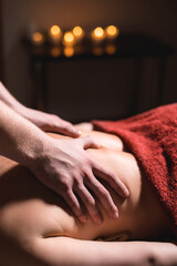 Obraz na płótnie Canvas Massage of a female back in a dark room of a spa salon. Male masseur doing massage of the back of the body and lower back