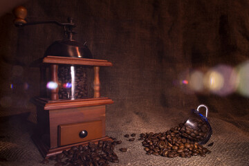 A cup of coffee beans stands on a rough cloth. Retro coffee grinder stands on sacking. Artistic...