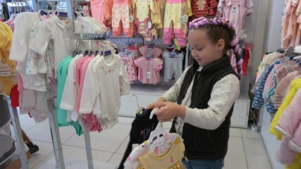Fethiye, Turkey - 25th of March 2021: 4K Girl chooses baby clothes in the kid shop
