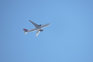 Airplane flying in the clear blue sky, bottom and side view. Commercial plane taking off and gaining altitude