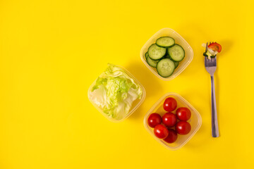 Containers with fresh vegetables on a yellow background