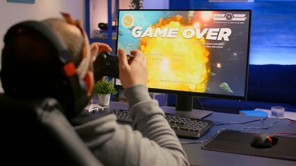 Competitive cyber pro gamer losing online video game tournament wearing professional headset. Pro player using joypad for space shooter championship sitting on gamining chair © DC Studio