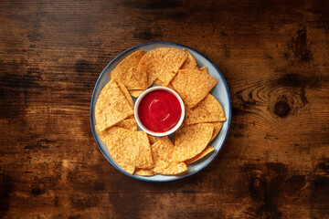 Nacho chips with a red sauce, overhead shot