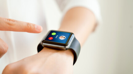 Woman hand touching on smartwatch to unlock and show call screen with friend.