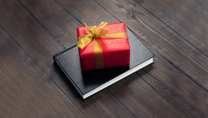 Closed Bible. Book. Gift in a red package with a gold bow. On a wooden table.
