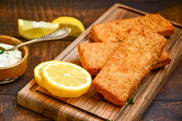  Fish and chips .Close up of   crispy breaded  deep fried fish fingers with breadcrumbs served with remoulade sauce and  lemon