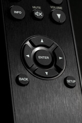 Close-up of Cursor buttons (select items with arrows up, down, right and left) and enter button on remote control for TV and audio in black color.