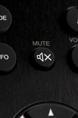 Close-up of Mute button (on - off audio) on remote control for TV and audio in black color.