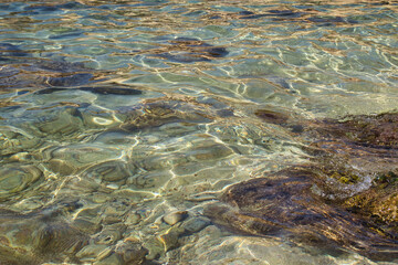 Ripples in the water with rocks and a jellyfish at Prajjet Bay in Malta.