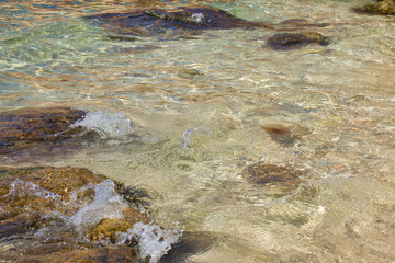 Water splashing on a rock near a jellyfish in the water at Prajjet Bay in Malta on a warm fall day.