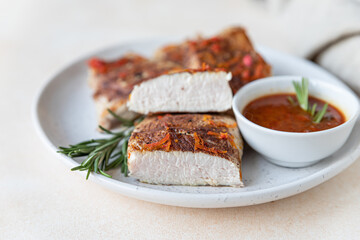 Fried turkey or chicken breast served with orange sauce and rosemary on a plate, light concrete background. Healthy food.