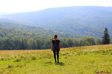 Fototapeta na wymiar The girl with a backpack the traveler enjoys in the summer and looks at the mountains. Wildlife. Carpathians.