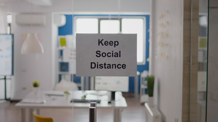 Fototapeta na wymiar Business glass interior office with keep social distance sign on the wall. Modern office space with nobody in it during global pandemic, coronavirus crisis