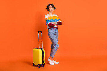Photo of upset shiny young woman wear wear striped sweater suitcase arms crossed isolated orange color background