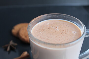 drink hot chocolate cocoa in a glass mug with cinnamon sticks and cookies on a black background with a place for text