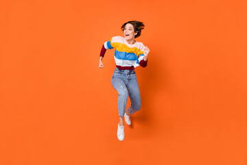 Fototapeta na wymiar Full length body size view of attractive amazed cheerful girl jumping running having fun isolated over bright orange color background