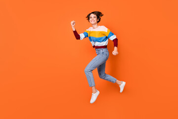 Fototapeta na wymiar Full length profile portrait of charming person jump running beaming smile isolated on orange color background