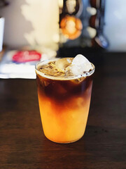 Iced coffee with orange - A plastic glass of americano mixed with craft soda and yuzu orange juice on blurred background, Refreshing summer drink concept.