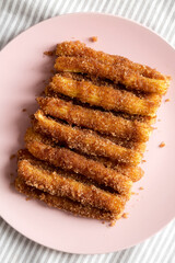 Home-baked Churro Bites on a pink plate on cloth, top view. Flat lay, overhead, from above. Close-up.