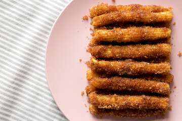 Home-baked Churro Bites on a pink plate on cloth, top view. Flat lay, overhead, from above.
