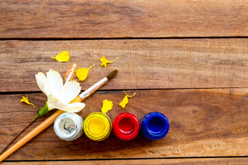 poster colour art, paintbrush and flowers of lifestyle arrangement flat lay postcard style on background wooden