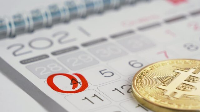 Cryptocurrency and calendar. Predicting the date buying or selling the e-currency. Person marking the day on the wall calendar with a red pen. Conceptual footage in close up