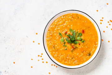 Lentil soup with vegetables at white stone table.