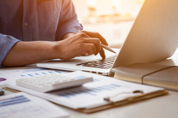 Close up Business man using calculator and laptop for do math finance on wooden desk, tax,...