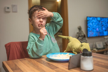 Boy unhappy with his lunch. Child boy eating boring food. Little boy is unwilling to finish his...