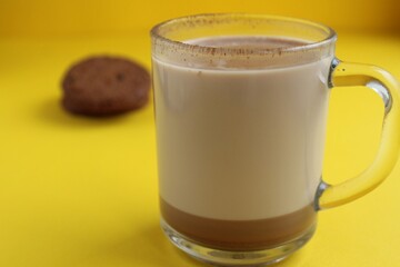 a cup of hot chocolate cocoa on a bright yellow background with room for a copyspace text