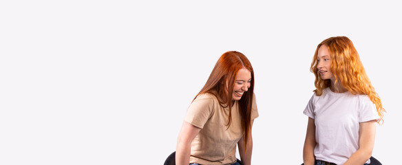 Banner,long format. The pastime of two red-haired girlfriends. Girls chat and smile on a gray background.