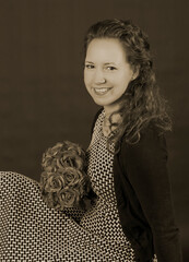 Portrait of young beautiful woman with bouquet of rose flowers. Sitting in a dress and curly hair. In brown vintage photo colors. Vintage, retro style from 1900