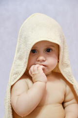 Baby girl after shower or bath with towel on head. Baby wearing hooded towel sitting on parents bed after bath or shower.