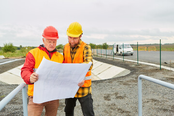 Architect and construction worker look at architectural drawing