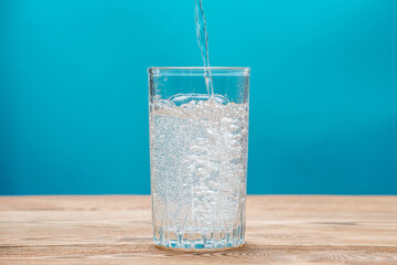 Pure carbonated water with bubbles in a glass on a blue background