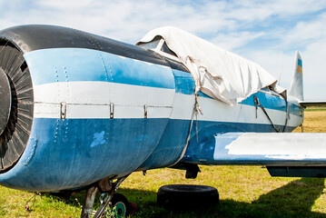Small old blue plane standing in summer field