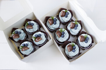 Blue cupcakes decoraited with blueberry and chocolate. Berry cupcakes in paper box. Muffin background