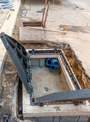 Construction of a distribution line for broadband infrastructure with fiber optic cables. Junction box with cast iron manhole cover.