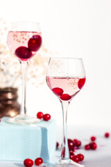 two glasses of pink gin infused with cranberry and cherry on light background closeup, berry liquor or any alcohol cocktail among red berries, minimalism