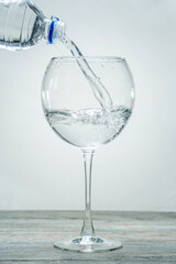 In a beautiful elegant glass on a stem is pouring from a bottle of clean healthy water
