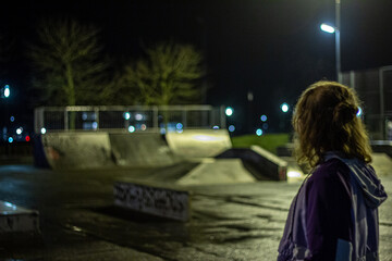 Teenage girl in the skate park all alone at night. 