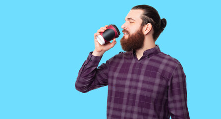 Photo of handsome bearded hipster man drinking coffee over white background